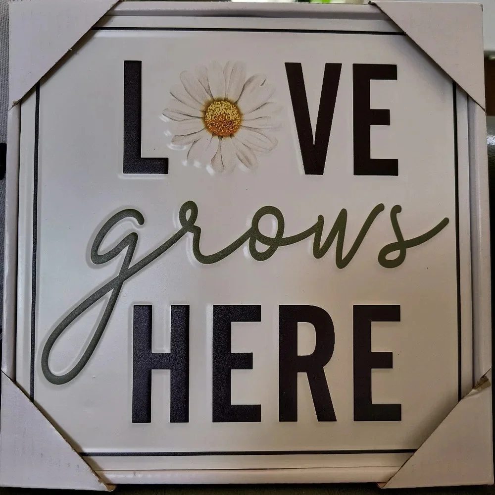 White yellow black metal sign Love Grows Here with a daisy on it home decor